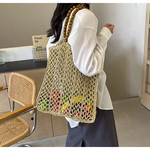 Detail of woven straw tote bag with brown wooden bead handles for summer beach style