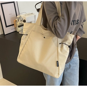 Detail of beige canvas tote bag with black drawstring and magnetic clasp closure