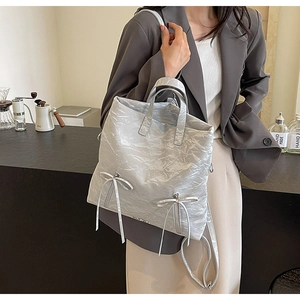 Detail of silver metallic wrinkled PU tote bag with ribbon bow and textured surface