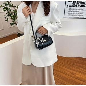 Detail of black PU leather handbag featuring a pearl bow, heart charm, and silver twist lock
