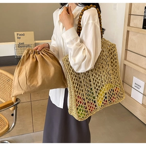 Close-up of woven straw tote bag featuring wooden bead handles and a drawstring inner pouch