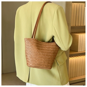 Detail of tan woven tote bag with herringbone pattern and brown leather straps