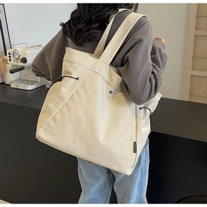 Detail of canvas tote bag with side drawstring and front metal buckle pocket