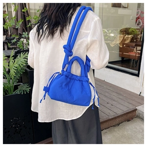 Outdoor style view of a Klein blue quilted drawstring crossbody bag with knotted shoulder strap