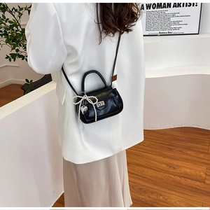Detail view of black PU leather crossbody bag with pearl bow and heart pendant