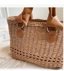 Detailed view of straw tote bag with knot leather handle and gold metal ring attachment