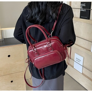 Dark red faux leather Boston bag detail with side ribbon bow and sleek zipper pocket
