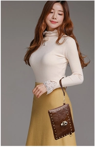 Detail of vintage brown leather handbag with rivet accents and skull charm decoration
