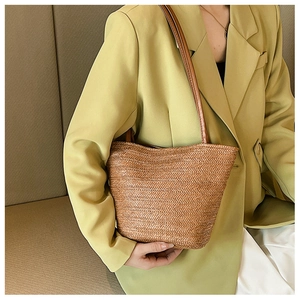 Detail of hand-woven straw tote bag with brown leather straps and herringbone texture