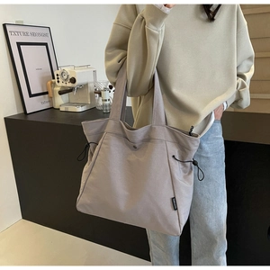 Detail of grey canvas tote bag with drawstring side and polished hardware closure