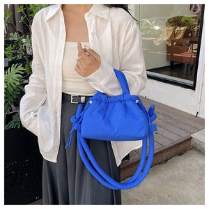 Close-up of vibrant blue polyester drawstring bag featuring quilted texture and knot detail