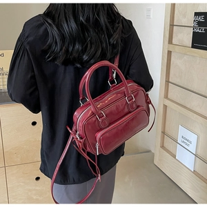 Detail of burgundy vintage oil wax PU leather handbag with silver zippers and handles