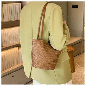 Detail of a brown woven tote bag with herringbone pattern worn over the shoulder
