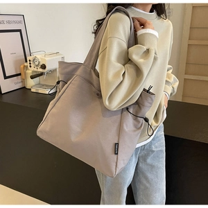 Detail view of canvas tote bag showing side drawstring pocket and black brand label