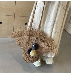 Dettaglio della borsa in paglia bohémien con bordi a frange e pompon colorati decorativi