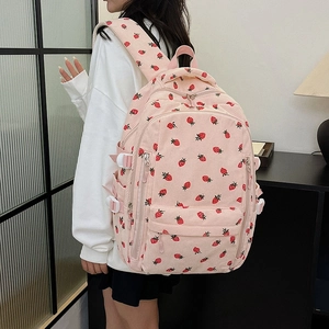 Sac à dos en velours rose avec motifs fraises porté par un mannequin dans un intérieur