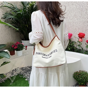 Detail of canvas tote bag with brown leather trim shown in an outdoor garden setting