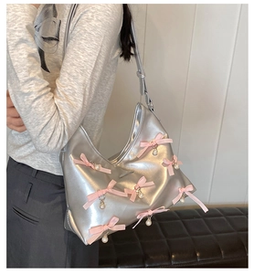 Silver PU leather hobo bag with pink ribbon bows and pearl charms shown on a model