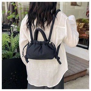 Rear view of model wearing a black quilted puffer backpack with drawstring closure