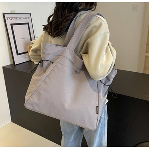 Detailed side view of canvas tote bag with adjustable drawstring and wide strap