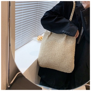 Detailed close-up of natural beige straw woven tote bag with intricate texture and dual straps