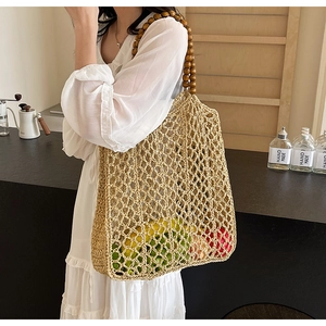 Detail of woven straw tote bag with dark wooden bead handle and openwork structure