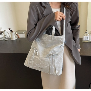 Silver PU tote bag detail with double zippers and bow ties worn by a model