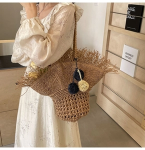 Dettaglio della borsa in paglia intrecciata con frange bohémien e pompon colorati