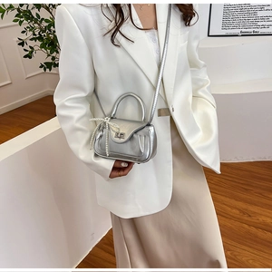 Detail of silver metallic handbag featuring pearl bow charm and metal twist lock