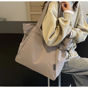 Detail of taupe canvas tote bag with side drawstring design shown on model for daily use