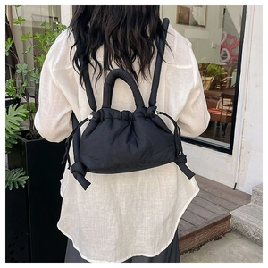 Detail of black puffer cloud backpack featuring nylon texture and padded shoulder straps