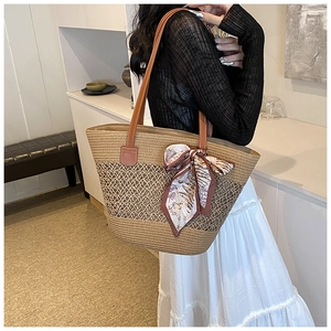 Detail of hand-woven straw tote with hollow pattern and floral scarf ribbon