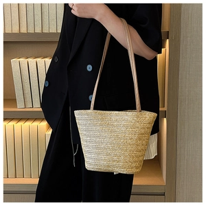 Straw tote bag with brown leather straps shown on shoulder in library setting