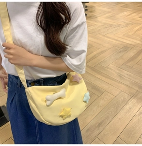 Détail du sac bandoulière croissant jaune avec étoiles en peluche et charme d'os mignon