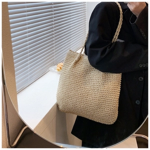 Straw shoulder tote bag with tight fiber weaving shown on model in warm lighting