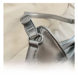 Detail of silver PU leather crossbody bag showing D-ring hardware and pink ribbon bow