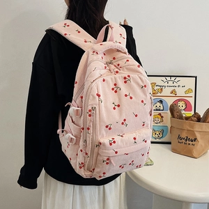 Détail du sac à dos en velours côtelé rose avec imprimé cerise et bretelles
