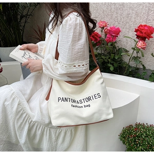 Canvas tote with brown leather trim held by a model in a floral outdoor garden setting