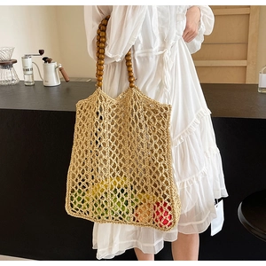 Detail of woven straw tote bag with round wooden bead handles in a lifestyle setting