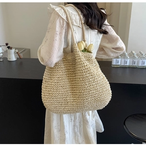Close-up of beige woven straw shoulder bag with textured weave in a cafe setting