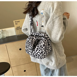Détail d'un sac bandoulière à motif léopard avec double fermeture éclair et poignée