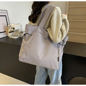 Detail view of large grey tote bag featuring side drawstrings and shoulder strap