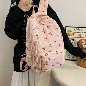 Détail d'un sac à dos en velours côtelé rose avec motifs cerises et poches latérales