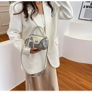 Detail of silver metallic PU bag featuring pearl bow charm and heart metal pendant
