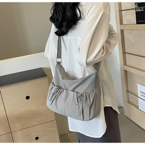 Seitenansicht einer grauen Nylon-Umhängetasche mit Kordelzugtaschen und Silberschnallen