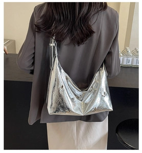Detail of silver metallic crescent bag with butterfly charm and pleated texture