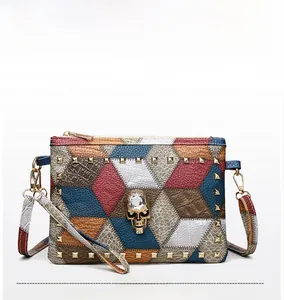 Detail of multi-color patchwork leather bag featuring golden skull and rivet studs