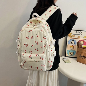 Détail d'un sac à dos en velours côtelé beige à motif cerises avec boucle latérale et poche
