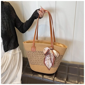 Detail of handmade straw tote bag featuring woven mesh texture and pink floral silk scarf