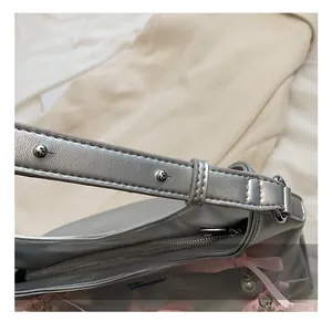 Detail showing the adjustable silver metallic shoulder strap and zipper closure of the PU bag